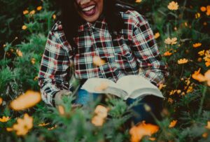 "woman laughing while reading outside"