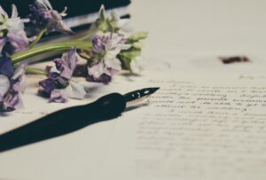 "Letter with flowers and a fountain pen laying on it"
